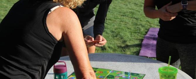 Players gather around the board to roll the die for their next workout. Orange challenge cards stop play so everyone can compete head-to-head.